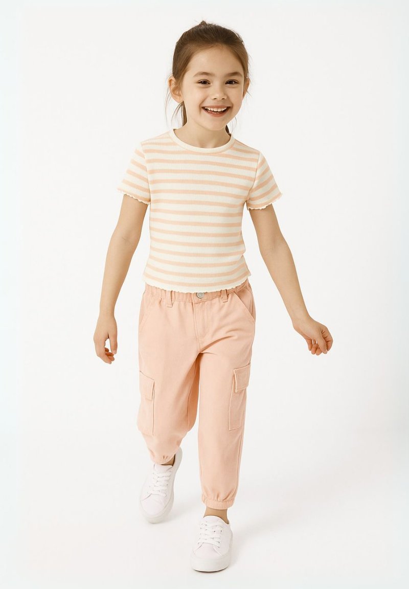 T-shirt rose clair à rayures à manches courtes associé à un pantalon cargo rose clair avec des poignets élastiques et des poches, complété par des baskets blanches.