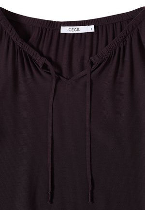Mørk lilla top med rund halsudskæring, med et nøglehul-design og justerbare snore. Blødt stof med glat overflade. Brandlabel synlig.