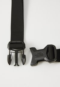 Fekete nylon heveder, két oldalsó eltávolítható műanyag csat, az egyiken "THE NORTH FACE" logóval; sima felület, tartós kivitel.