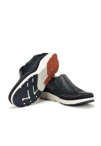 Zapatos de piel navy de tipo slip-on con suelas blancas, costuras en contraste y una suela de goma con patrones de relieve y un pequeño acento naranja.