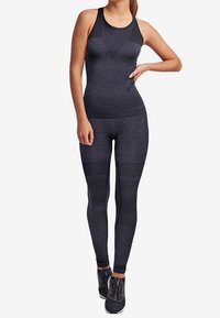 Svart sportoutfit med en åtsittande linne med meshpaneler och högmidjade leggings med texturerade horisontella ränder.