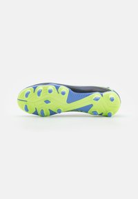 Suela de zapatilla deportiva negra y verde con una superficie texturizada, que presenta acentos azules y múltiples clavos de tracción para agarre.