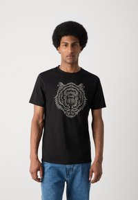 Camiseta de algodón negra con un diseño detallado y texturizado de la cara de un tigre en color claro, cuello redondo y mangas cortas.