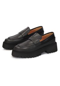 Mocassins en cuir noir avec un bout arrondi, un large bandeau décoratif et une semelle en caoutchouc épaisse avec des rainures profondes. Texture lisse sur le dessus.