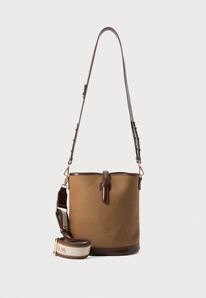 Brown fabric bucket bag with dark brown leather accents. Adjustable strap features a decorative woven section with text. Smooth texture, minimalist design.