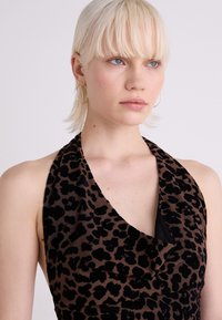 Haljina s uzorkom leoparda, s halter izrezom, koja se odlikuje drapiranim dizajnom u smeđoj i crnoj boji. Mekana, teksturirana tkanina s elegantnim dekolteom.