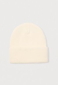 Soft cream-colored knitted beanie hat with folded cuff on a plain light background.