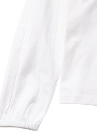 Camicia bianca a maniche lunghe con polsini arricciati e fessure laterali. Realizzata in morbido cotone, presenta un design semplice senza motivi o accenti.