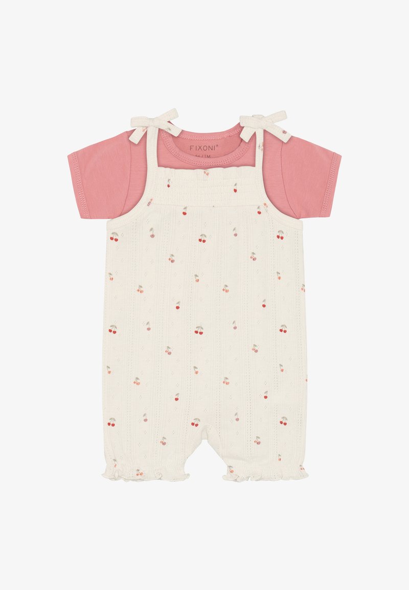 Camiseta rosa de manga corta bajo un mono color crema con pequeños estampados de cerezas y tirantes anudados en los hombros para un bebé.