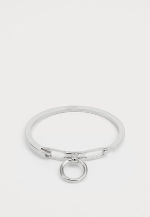 Bracelet en argent avec un design de jonc lisse et arrondi, comprenant un anneau circulaire central et un détail décoratif de fermoir.