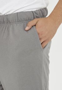 Grå bomullsjoggers med elastisk midja, sidofickor och en subtil logotyp broderad i en ljusare nyans på låret.
