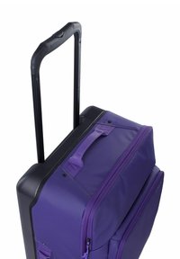 Valigia viola con ruote e base nera. Presenta un manico retrattile, due manici laterali e scomparti con cerniera per la conservazione.