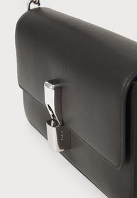 Borsa a spalla nera in pelle con finitura texture, forma rettangolare e dettaglio in metallo argentato. Design con pattina chiusa e senza motivi visibili.