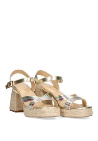 Sandalias de tacón dorado metálico con tiras de colores entrelazadas y un tacón cuadrado envuelto en yute. Textura suave con correa para el tobillo ajustable.