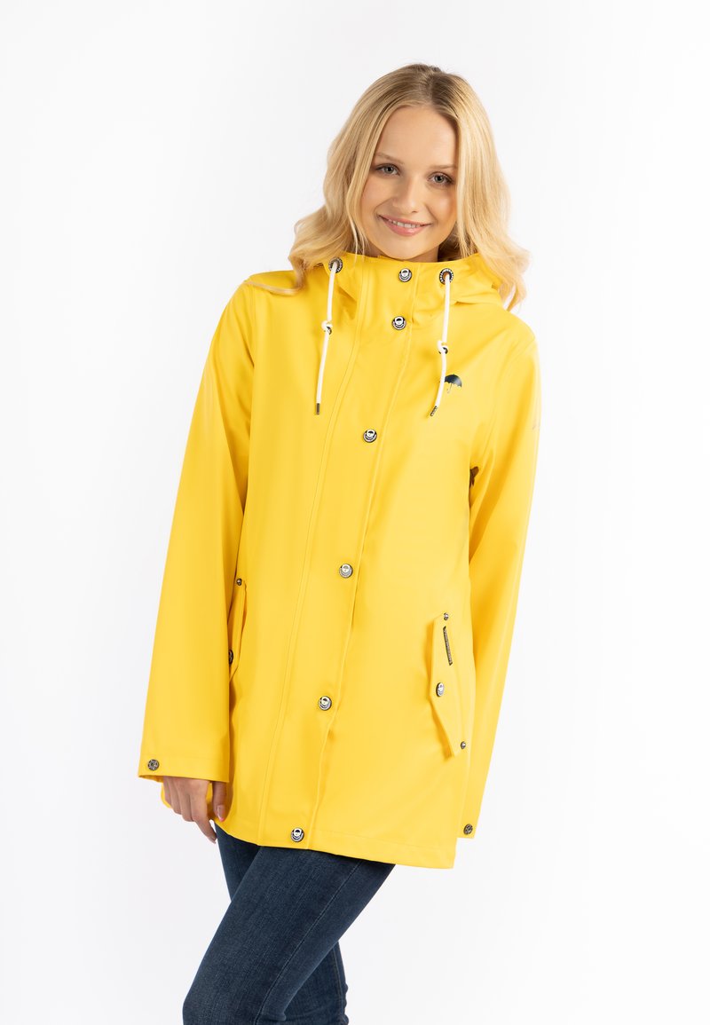 Cappotto impermeabile giallo con cappuccio, bottoni a pressione e due tasche laterali. Presenta una superficie liscia e cordoncini regolabili.