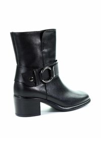 Botas de cuero negras hasta el tobillo con punta redondeada, tacón medio y una banda ancha con un detalle de hebilla metálica circular. Textura suave.