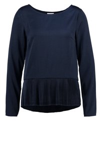 Haut à manches longues bleu marine avec un col rond, doté d'une texture plissée à l'ourlet. Le tissu lisse contraste avec le bas structuré.