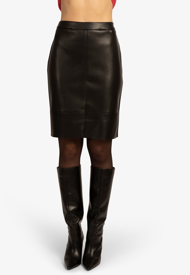 Jupe crayon en cuir noir avec une texture lisse, un design ajusté et un logo discret au niveau de la taille. Coupe au genou.