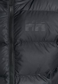 Giacca a vento nera con zip frontale e logo opaco. Realizzata in materiale liscio e leggero con sezioni trapuntate cucite.