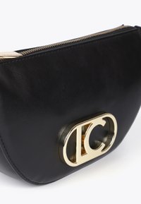 Svart läderkuvert med en guldsymbol i mitten och en dragkedja upptill, som visar en stilren, modern design.