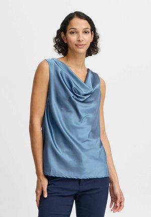 Satijnen top met een cowl-hals in gedempt blauw en een mouwloos ontwerp. Soepele textuur, draperende voorkant en rechte zoom. Gekozen met donkere broek.