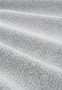 Ljust grått tyg med en mjuk, texturerad yta som visar subtila åsar och en lätt glans. Idealisk för kläder eller stoppning.