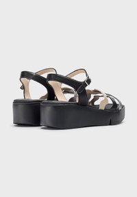 Sandalias de plataforma de cuero negro con un acabado texturizado, que cuentan con múltiples correas anchas y una correa de tobillo con hebilla para un ajuste seguro.
