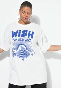 Wit katoenen T-shirt met blauwe grafische tekst "WISH YOU WERE HERE" met een visillustratie en zonnestraalontwerp. Losse pasvorm, korte mouwen.