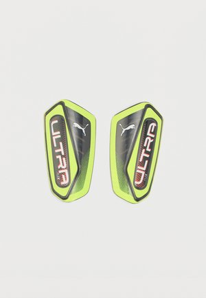 Paar gelb-schwarzer Puma Ultra Flex Fußball-Schienbeinschoner mit roter Schrift auf weißem Hintergrund.