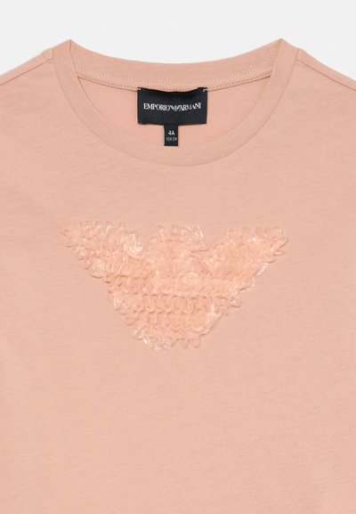 Rózsaszín, kerek nyakú póló, összegyűjtött anyag részlettel, amely a gallér alatt sas logót formál, valamint Emporio Armani címke a nyakvonal belsejében.
