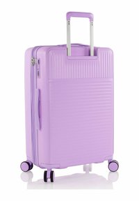 Lila Hartschalentrolley mit vertikalen Rillen, teleskopischem Griff und vier drehbaren Rollen für eine einfache Handhabung.