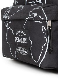 Bolsa de lona negra con diseño de mapa mundial en blanco, con etiquetas "Take Care with Peanuts" y "Eastpak". Incluye cierre de cremallera y detalle de cuerda.