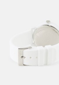 Reloj de pulsera de silicona blanca con una correa texturizada, hebilla de metal plateado y caja redonda con un fondo liso y reflectante.