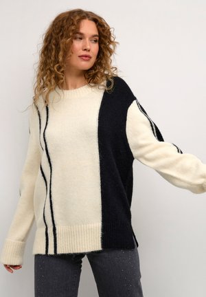 Maglione a maglia in crema e blu navy, con pannelli a contrasto e polsini a coste. Texture morbida con dettagli a righe verticali.