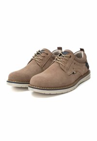 Zapatos de ante marrón con cordones y punta redonda, suela de goma blanca en contraste y costuras decorativas. Presenta un panel azul marino y una pestaña de tira.