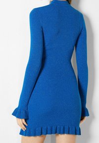 Robe en tricot d'un bleu vibrant avec une texture côtelée. Présente des manches longues, des poignets volants et un ourlet évasé. Détail de finition scintillante.