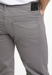Grijze katoenen blendbroek met een gladde textuur, voorzien van een enkele achterzak, contraststiksel en een leren label op de tailleband.