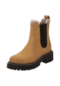 Bottine en cuir tan avec des panneaux élastiques latéraux noirs, doublure en fausse fourrure et une semelle en caoutchouc noir épaisse avec des crampons prononcés.