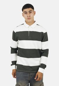 Polo a maniche lunghe con righe orizzontali verdi e bianche, colletto e polsini a coste. Realizzato in tessuto di cotone, presenta una patta con bottoni.