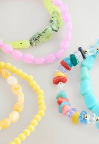 Bunte Perlenarmbänder mit rosa, gelben, grünen und blauen Steinen in verschiedenen Formen und Größen, mit glatten und glänzenden Oberflächen.