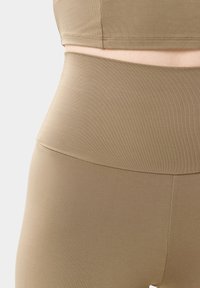 Hnědý žebrovaný sportovní podprsenka a legíny s vysokým pasem, vyrobené z hladkého, elastického materiálu s bezešvým designem a bez viditelných kovových částí.