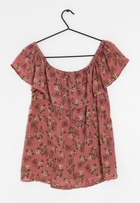 Top floreale off-shoulder in un colore rosa tenue, con rouches raccolti lungo il colletto e un tessuto leggero e testurizzato.