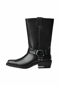 Black leather knee-high boot with a square toe, flat heel, and a decorative strap with metal accents around the ankle. Features a smooth texture.