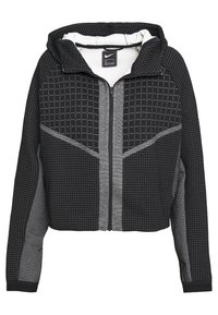 Černá zkrácená mikina s kapucí a předním zipem. Má geometrické vzory z teček, zateplený vnit řek a kontrastní texturované panely na rukávech.