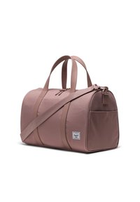 Sac de sport rose en tissu, avec deux poignées et une bandoulière amovible, fermeture zippée et une poche latérale avec un patch logo.