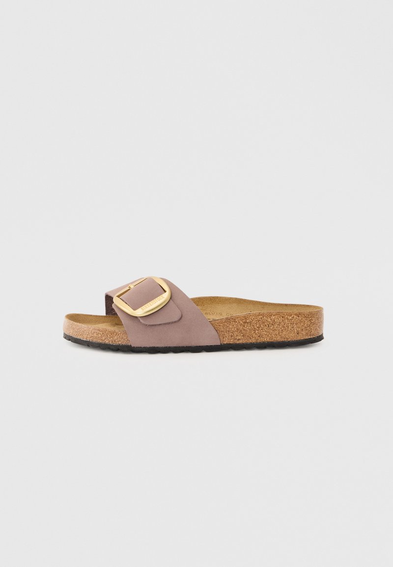 Brun korkfotbäddssandaler med mjukt mauve ovansida, med en stor guldspänneaccent. Platt sula, avslappnad design.