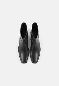 Černé kožené kotníkové boty s špičatou špičkou, postranními zipy a hladkým povrchem. Elegantní design s minimalistickou estetikou.