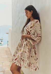Lichtgewicht, gestreept jurkje met bruine en roze vlekken op een crèmekleurige achtergrond; heeft een ontspannen pasvorm en kimono-stijl mouwen.
