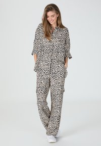 Leopard print two-piece outfit made of lightweight fabric. The top features a button-up design with short sleeves; pants are loose-fitting with pockets.