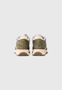 Baskets en suede vert avec une semelle blanche et rose pastel, présentant un dos de talon en tissu doux et un logo sur le capuchon du talon.